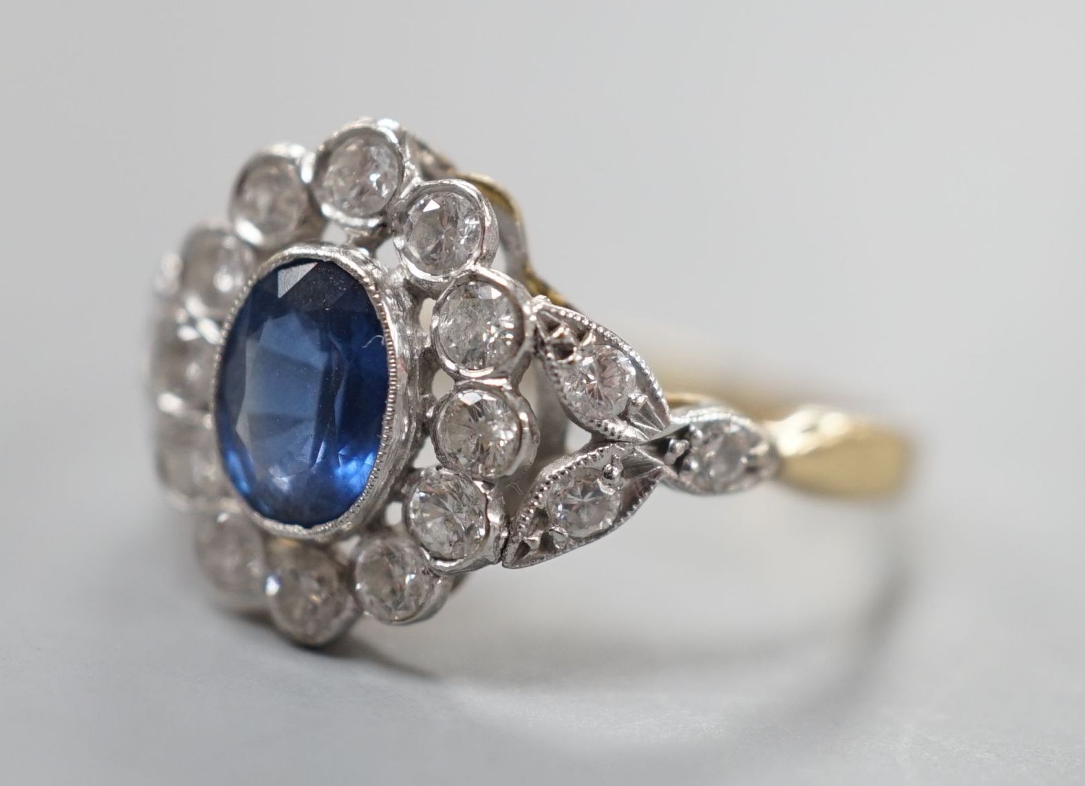 A yellow metal, sapphire and diamond set oval cluster ring, size T, gross weight 3.8 grams.